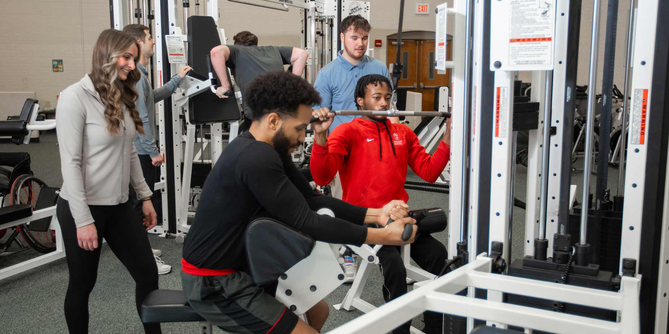 student trainers instructing other students how to properly lift weights