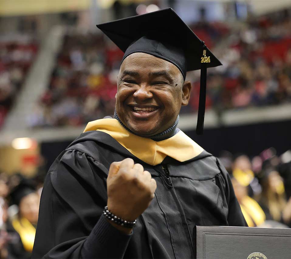 An MSW graduate pumping his fist at commencement